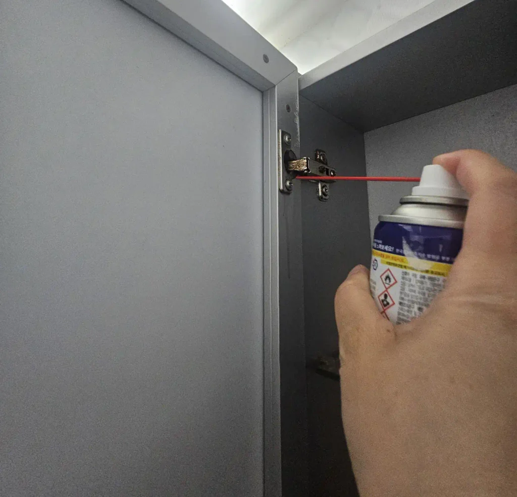 싱크대 경첩에 WD-40을 분사하는 모습